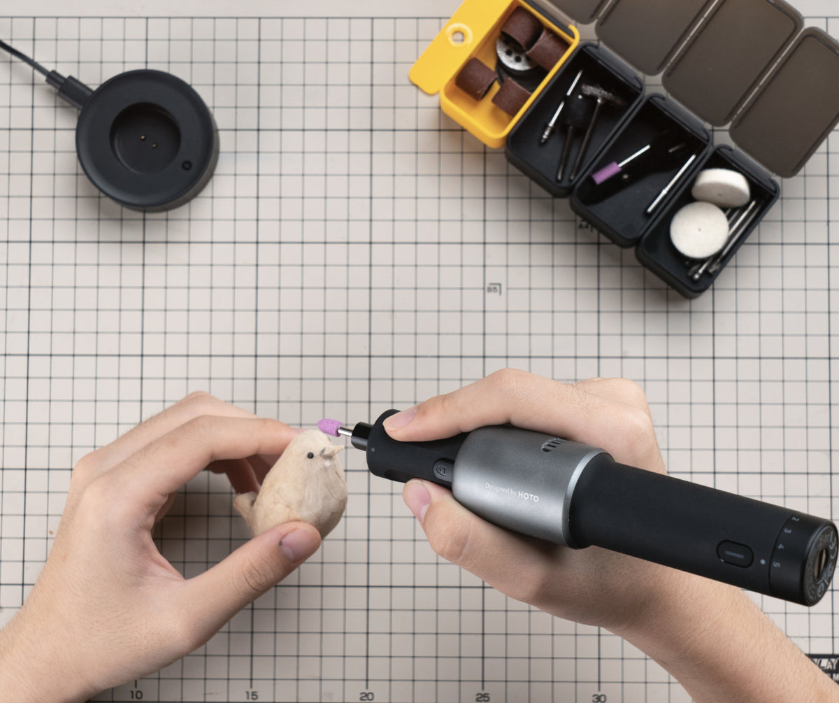 HOTO rotary tool used one-handed beside its charging dock and modular accessory boxes
